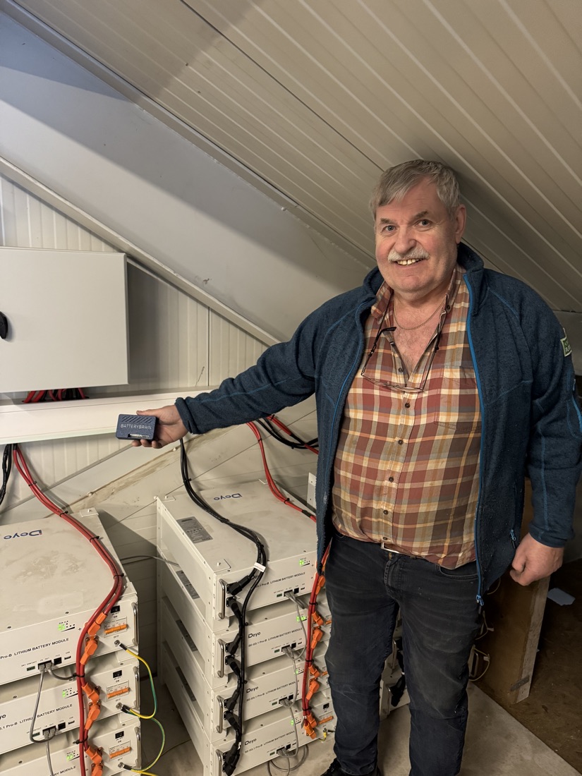 En kunde holder en BatteryBrain ved siden av batterimodulene i sitt eget anlegg.