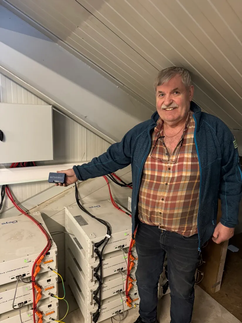 En kunde holder en BatteryBrain ved siden av batterimodulene i sitt eget anlegg.