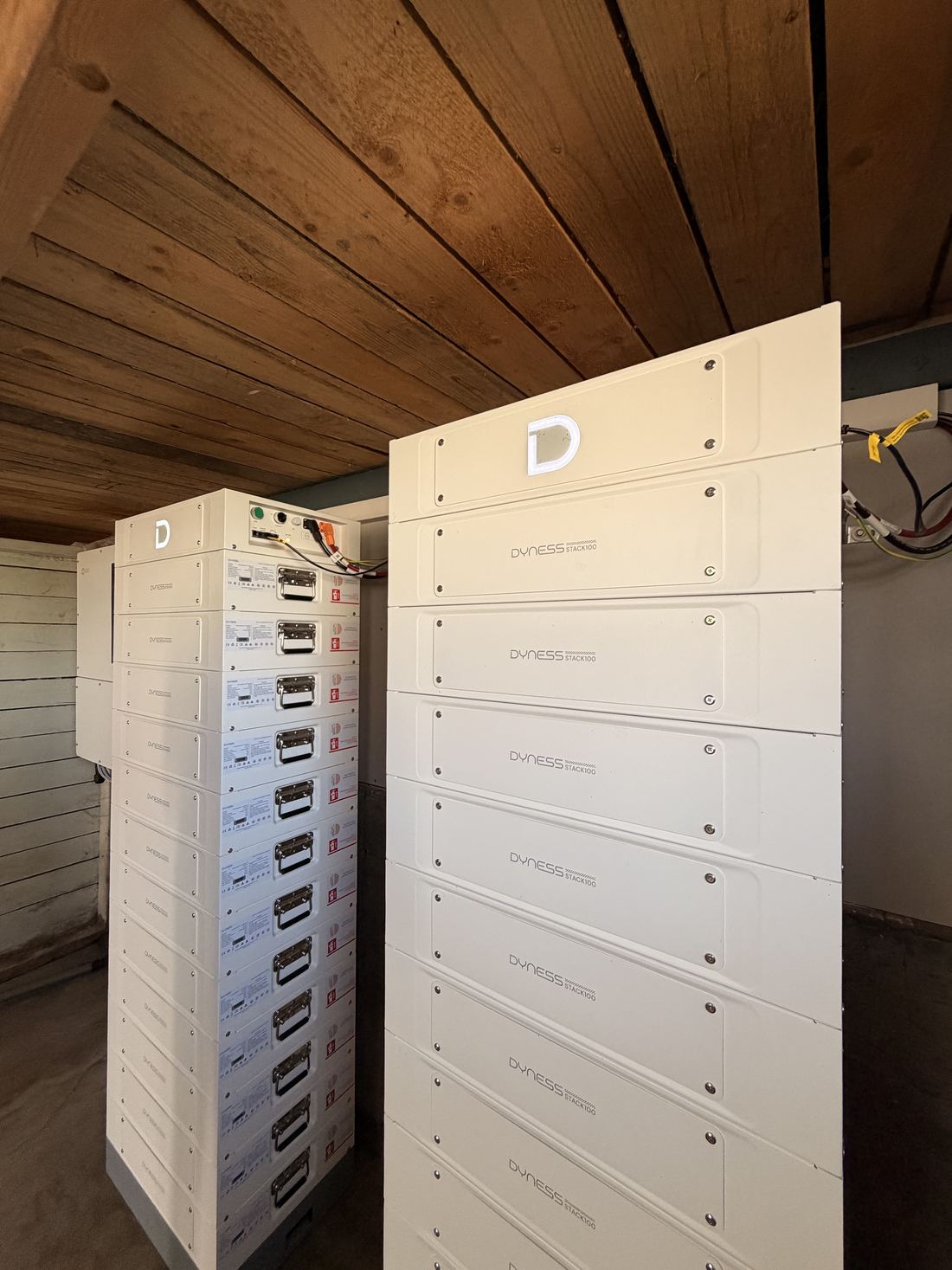 To tårn med stablede batterimoduler fra Dyness i et rom med trepanel i taket