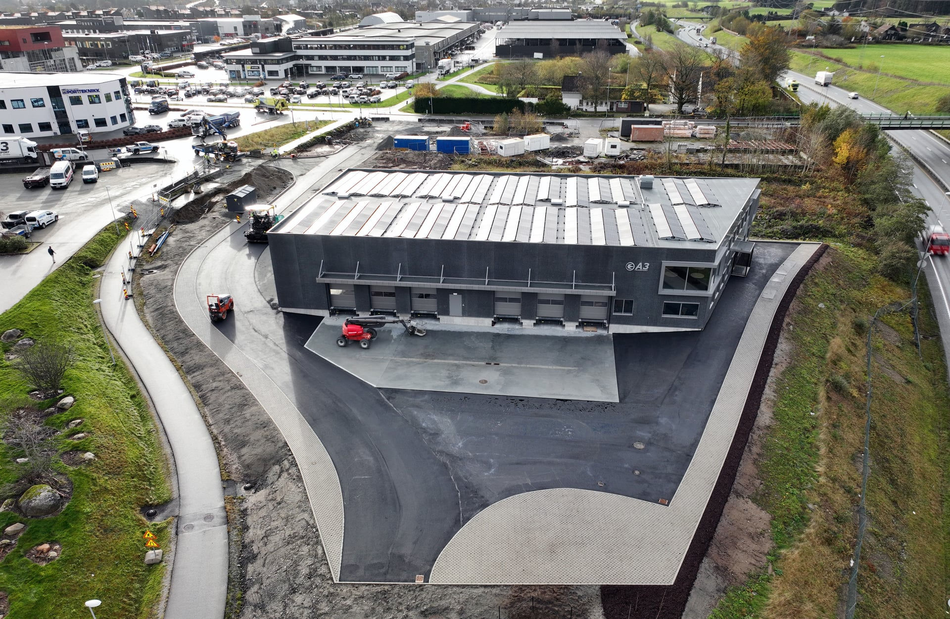 Nytt næringsbygg for et transportselskap i Sandnes sett ovenfra, med solceller på taket og lasteramper mot gårdsplassen