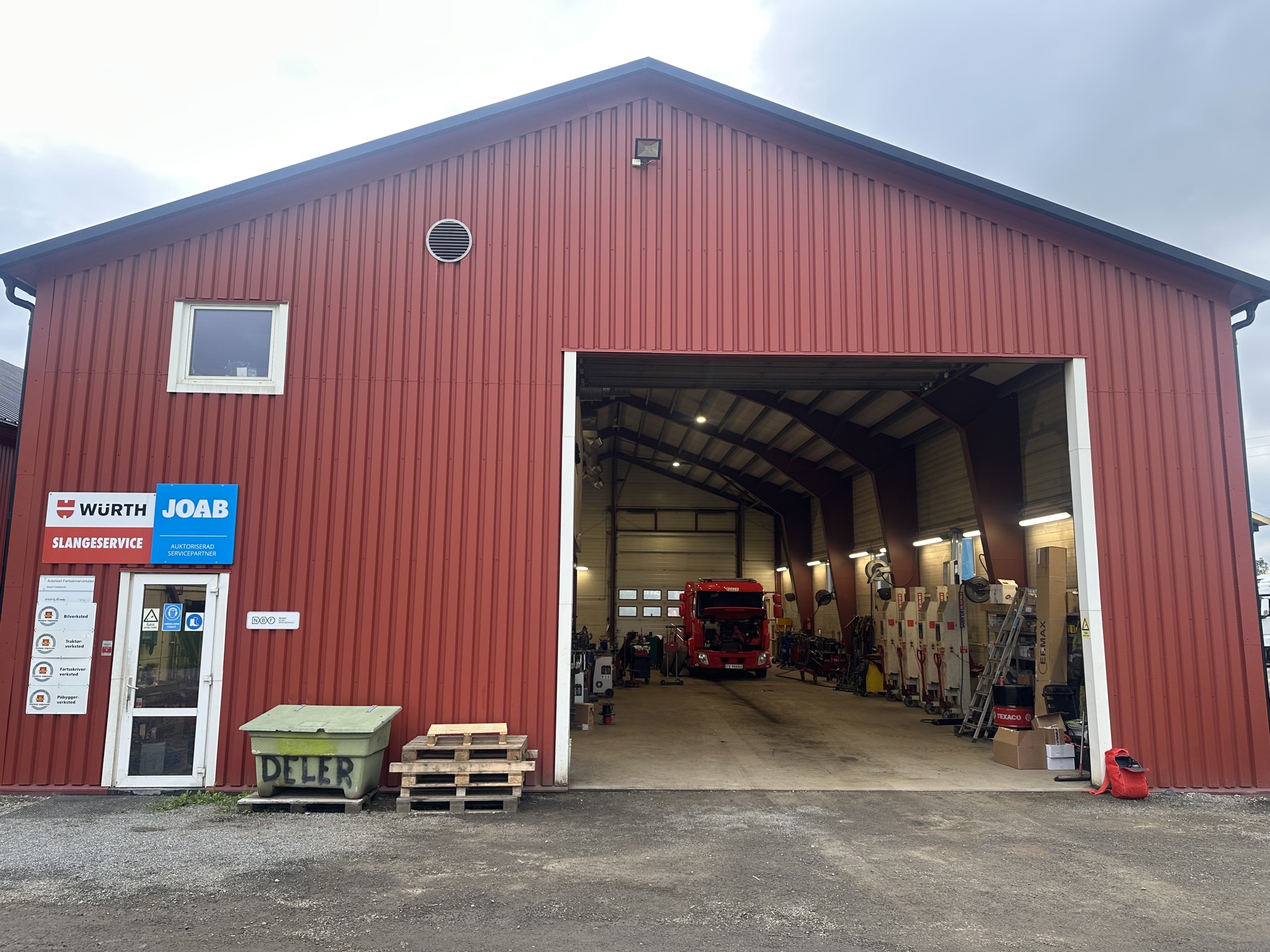 Den røde verkstedhallen på Trettemo med stor port åpen og en lastebil inne til service